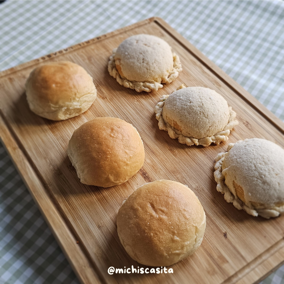 Pan de coco and semitas de yema arrange on a wooden cutting board.